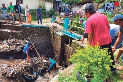 Petugas irigasi saat tengah membongkar sampah yang menjadi menumpuk di pintu air Kalianget. Sejumlah ban bekas tampak menumpuk di dasar saluran air. (Istimewa)