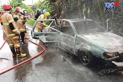 Tim damkar Kota Magelang menyemprotkan air ke mobil yang terbakar  di Jalan Soekarno Hatta, Canguk Kota Magelang, Rabu (12/10). (Istimewa)