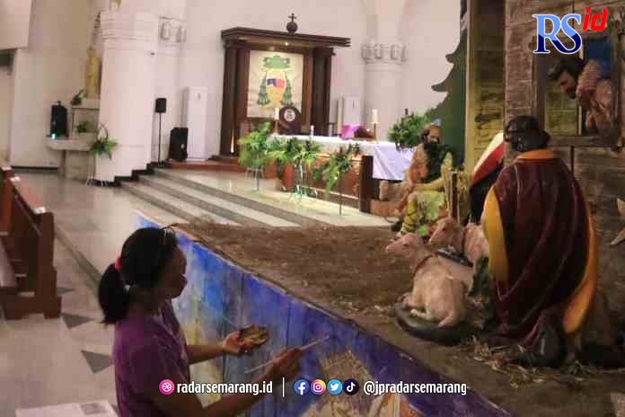 SAMBUT NATAL: Seorang jemaat tengah menyelesaikan pembuatan replika kelahiran Yesus dari koran dan kardus bekas di Gereja Katedral Santa Perawan Maria Ratu Rosario Suci untuk menyambut Natal 2022.(NUR CHAMIM/JAWA POS RADAR SEMARANG)