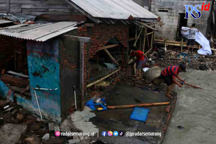 JEBOL: Warga Tambakmulyo RT 1 RW 15 Kelurahan Tanjung Mas memperbaiki rumahnya yang rusak dihantam gelombang tinggi. (NUR CHAMIM/ JAWA POS RADAR SEMARANG)