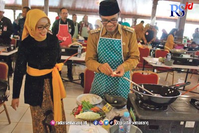 Ketua TP PKK Temanggung Eni Maulani Saragih memperhatikan suaminya, M Al Khadziq, mengupas bawang dengan tangan di Pendopo Pengayoman Kamis (22/12). (Istimewa)
