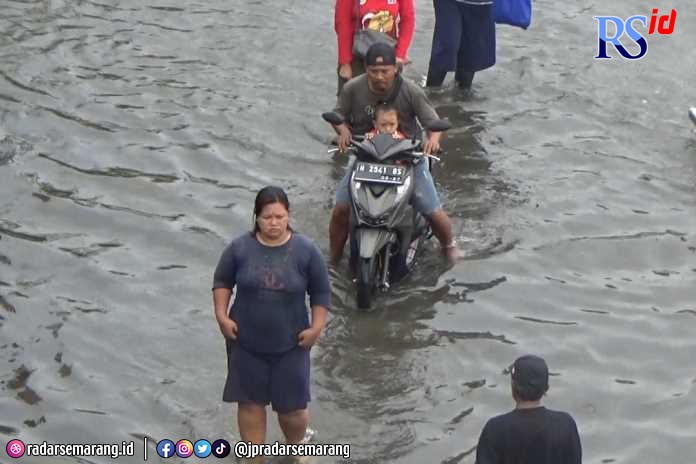 Warga melintasi banjir rob di kawasan Pelabuhan Tanjung Emas Semarang Jumat (2/12/2022). (M Ridwan/Jawa Pos Radar Semarang)
