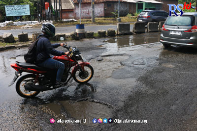 Pengendara motor menghindari jalan berlubang di Jalan Kaligawe Raya, Genuk, Semarang, kemarin. (NURCHAMIM/JAWA POS RADAR SEMARANG)