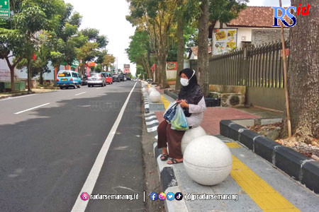 Seorang pengguna Jalan Diponegoro duduk di atas bollard ball sambil menunggu angkutan umum. (WARIH KARISMA/JAWA POS RADAR SEMARANG)