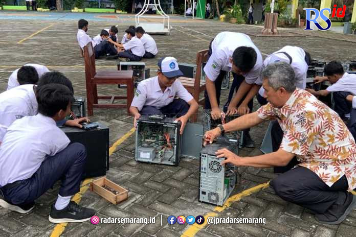 Kepala SMPN 31 Semarang Agung Nugroho bersama siswa melakukan pengecekan CPU masih berfungsi atau tidak setelah terendam banjir di halaman sekolah, Senin (2/1). (KHAFIFAH ARINI PUTRI/JAWA POS RADAR SEMARANG)