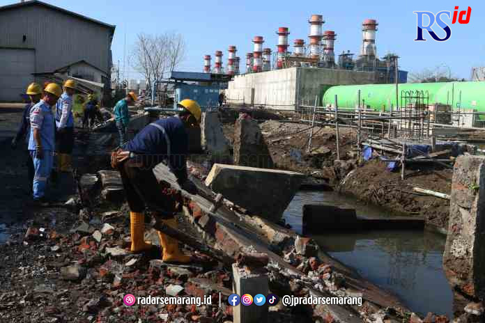 JEBOL: Sejumlah pekerja menghancurkan tembok pembatas antara PT Indonesia Power dengan Kawasan Industri PT Lamicitra yang jebol untuk dibangun kembali. (NUR CHAMIM/JAWA POS RADAR SEMARANG)