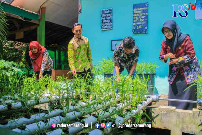 TERBAIK: Kepala SMP Negeri 22 Kota Semarang Rini Rusmiasih bersama para guru menunjukkan penanaman kangkung dengan sistem akuaponik di sekolahnya.(M IQBAL AMAR/JAWA POS RADAR SEMARANG)