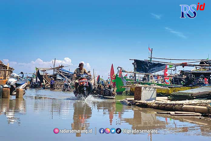 Seorang warga menerobos banjir rob di pesisir Bandengan Kamis (8/8) kemarin. (DEVI KHOFIFATUR RIZQI/ JAWA POS RADAR SEMARANG)