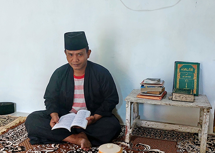 PRODUKTIF: Fauzi sedang membaca buku saat ditemui di rumahnya Desa Plakaran, Kecamatan Jrengik, Sampang, Sabtu (22/7).&nbsp;
