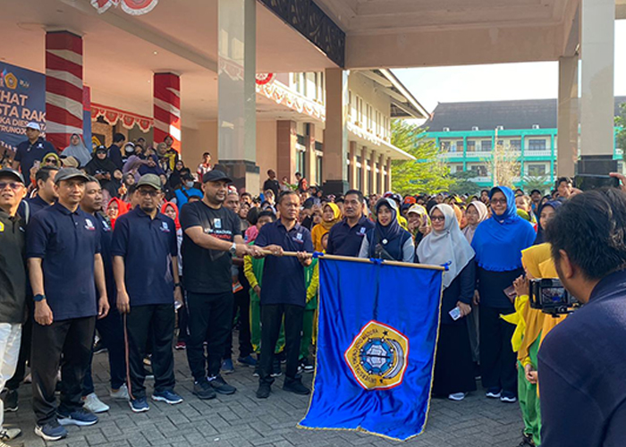 SIMBOLIS: Ketum Ika UTM Abdul Halim (topi hitam) dan Rektor UTM Safi&rsquo;, S.H., M.H. memegang bendera untuk pelepasan peserta jalan sehat di depan Gedung Rektorat UTM.