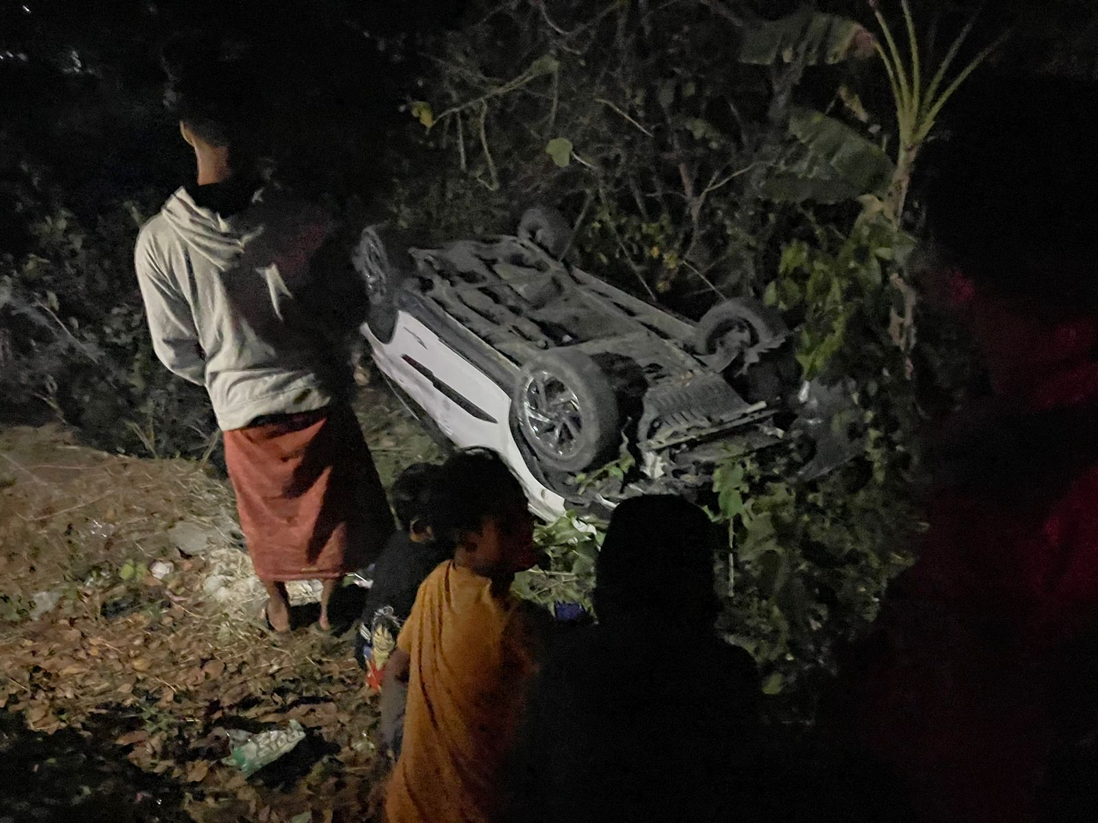 TERGULING: Warga melihat kendaraan Rush warna putih yang terlibat laka lantas di Jalan Raya Torjun, Jumat (11/8) malam. (MOH IQBAL AFGANI/RadarMadura.id)