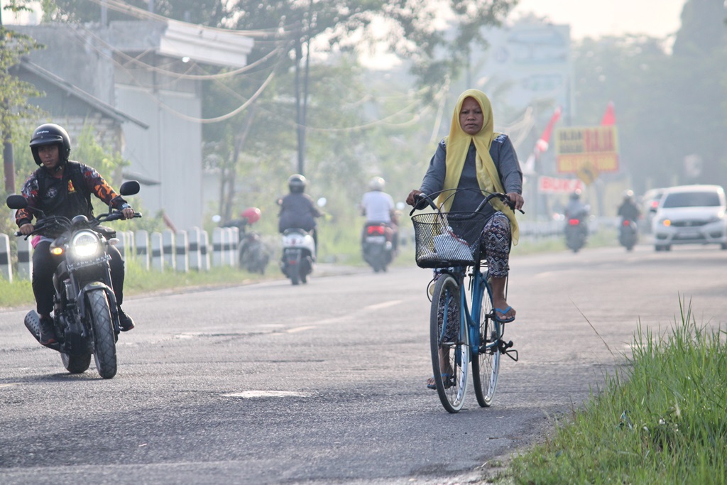 KESEHATAN: Seorang perempuan mengayuh sepeda saat pagi hari di Jalan Halim Perdanakusuma, Bangkalan, Jumat (11/8). (VIVIN AGUSTIN HARTONO/JPRM)