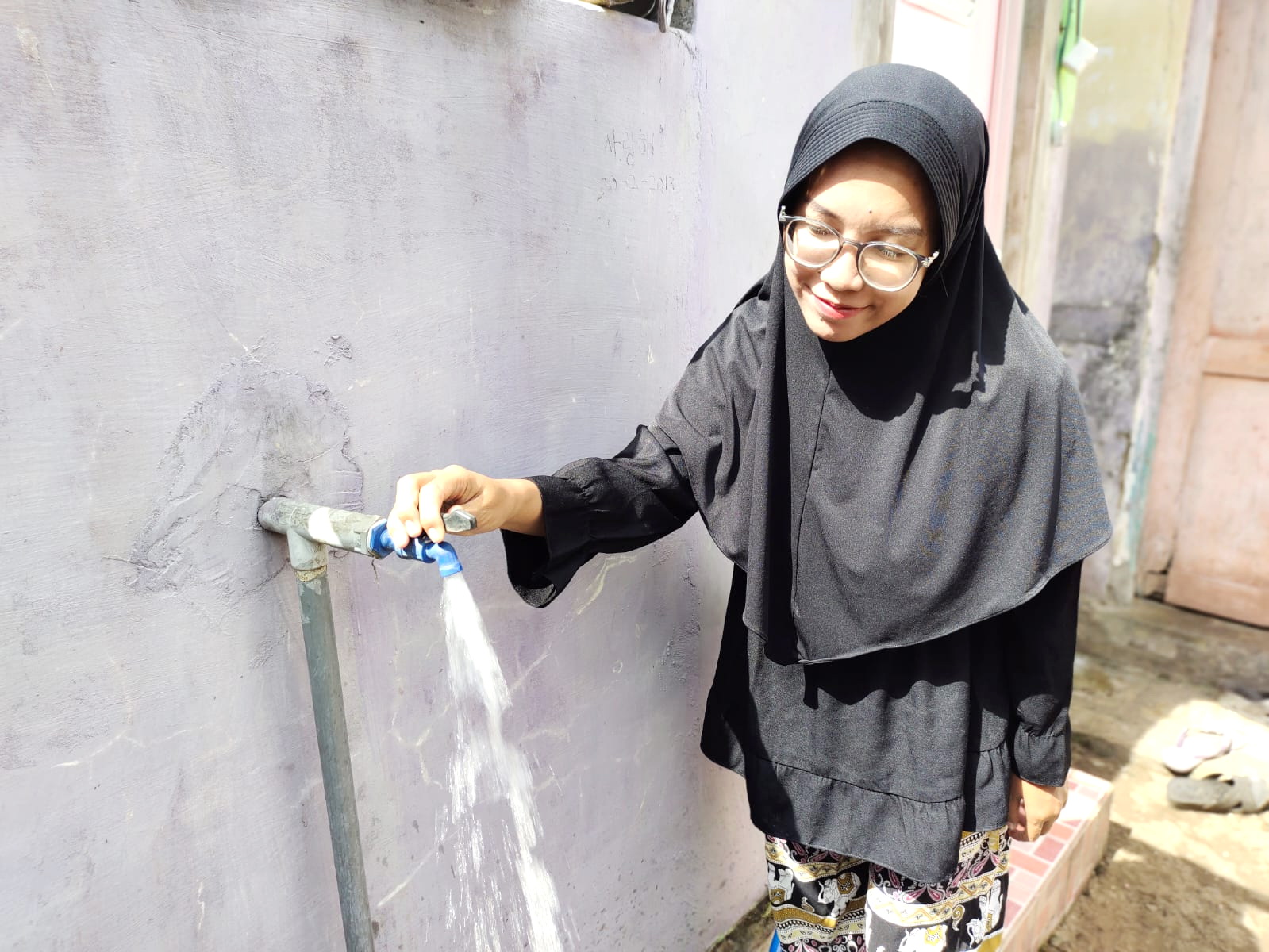 HEMAT AIR: Seorang perempuan mengambil air dari pipa, Minggu (13/8). (VIVIN AGUSTIN HARTONO/JPRM)
