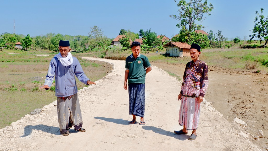 TERIK: Sekretaris Desa Karang Anyar Amiruddin (baju batik) meninjau akses jalan baru di Dusun Korcekor, Kamis (10/8). (MOH. IQBAL AFGANI/JPRM)