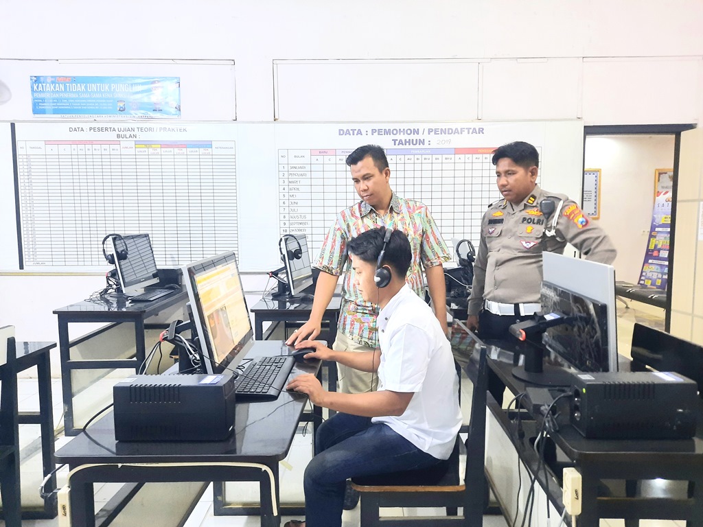 TELITI: KBO Lantas Satlantas Polres Sampang Iptu Syafriwanto dan Baur SIM Satlantas Polres Sampang Anto Surezki menghampiri peserta ujian teori, Jumat (18/8). (MOH. IQBAL AFGANI/JPRM)