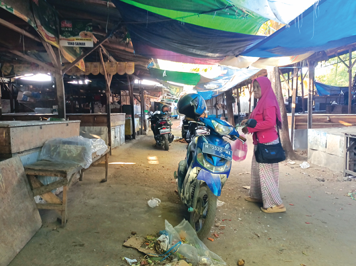 DIKELUHKAN: Warga berada di bawah atap terpal di antara lapak para pedagang daging di Pasar Anom Baru Sumenep, Kamis (7/9). (MOH. IQBAL/JPRM)