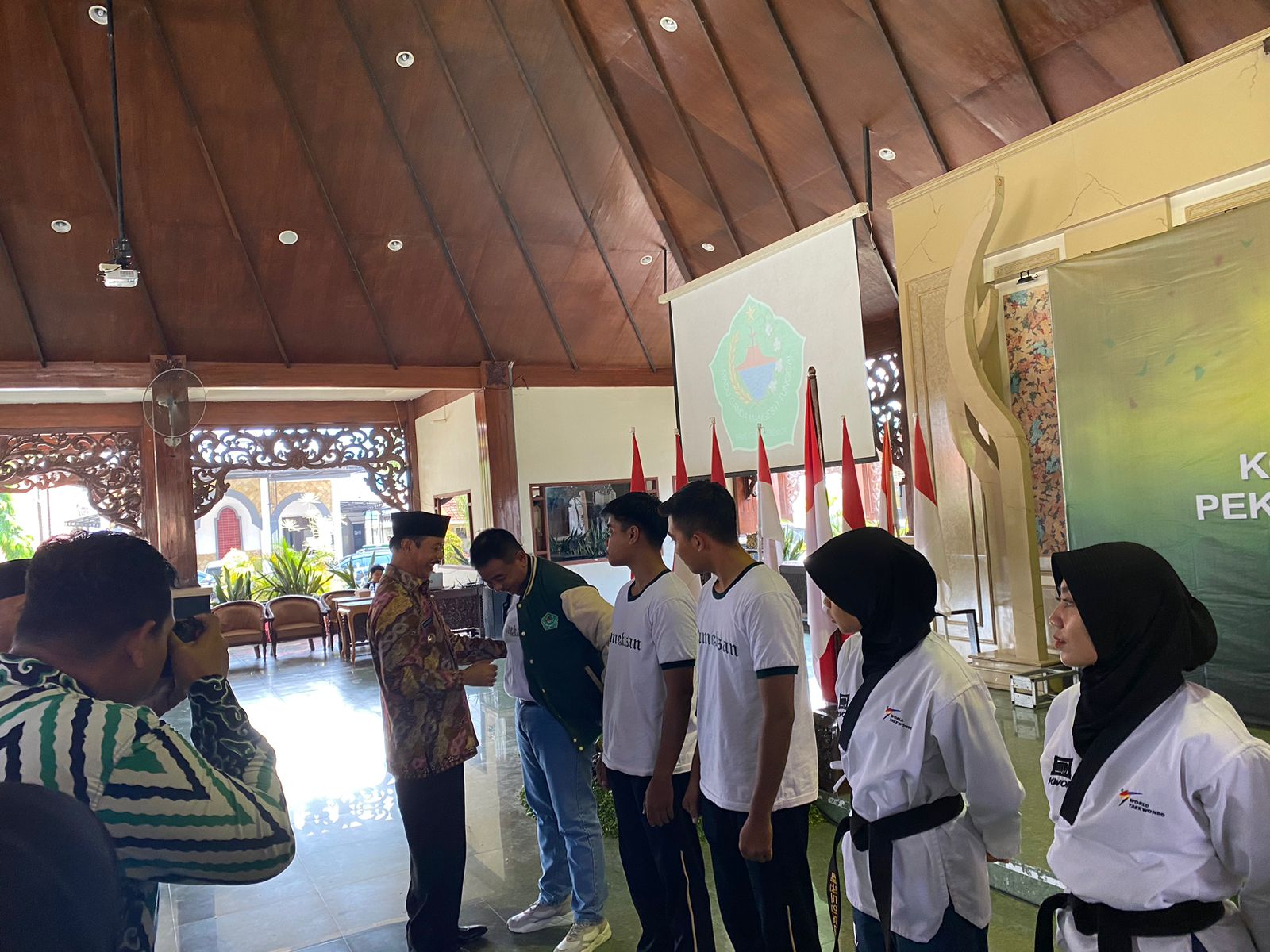 SIMBOLIS: Wakil Bupati Fattah Jasin memakaikan jaket kepada Manajer KONI Pamekasan Bambang Budianto di Pendopo Mandhapa Agung Ronggosukowati Kamis (7/9). (AYU LATIFAH/JPRM)