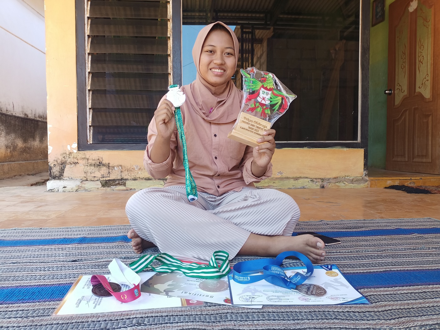 MEMBANGGAKAN: Shafiah Mudmainnatul Wasilah atlet silat asal Desa Jambu, Kecamatan Lenteng, Sumenep, menunjukkan medali yang berhasil diraih di rumahnya pada Rabu (6/9). (MOH. IQBAL/JPRM)