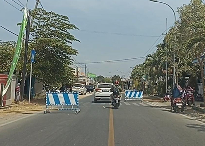 KANAN KIRI TUTUP: Pengendara melintas di jalan yang di sisi kanan dan kiri dipasang plang dan bambu tepat di depan SDN Jatra Timur 1, Kecamatan Banyuates, Sampang, Senin (4/9). (LUKMAN HAKIM AG./JPRM)