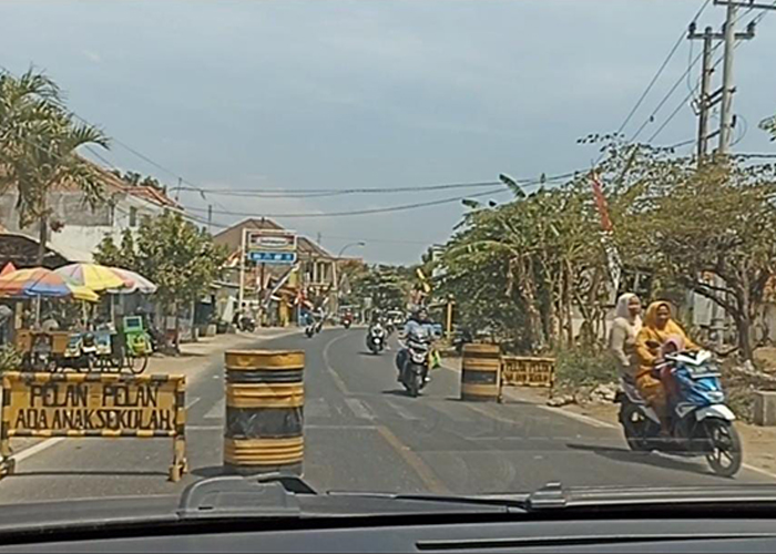 MENGGANGGU: Pengendara sepeda motor menghindari drum dan papan nama yang dipasang di jalan raya depan SDN Paseseh 1, Kecamatan Tanjungbumi, Bangkalan, Senin (4/9). (LUKMAN HAKIM AG./JPRM)