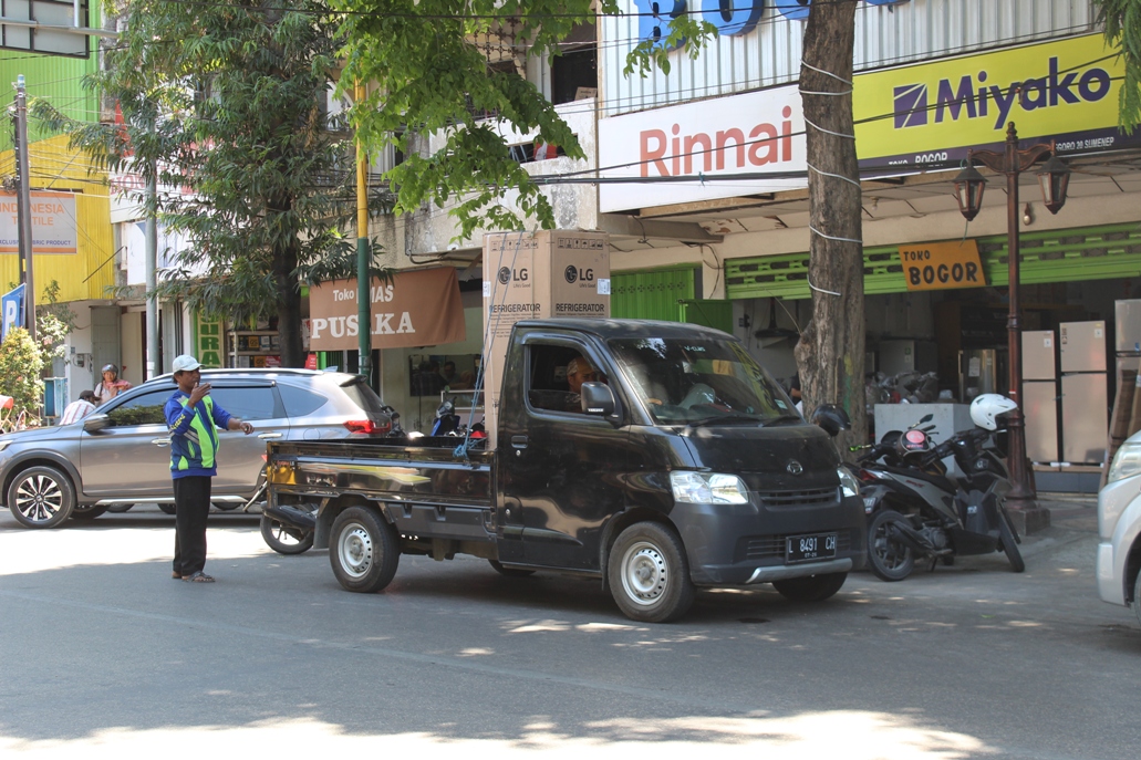 JUKIR: Juru parkir mengatur kendaraan yang diparkir di Jalan Diponogero, Sumenep, Minggu (10/9). (ERWIN MAULYDIN MAASBACH/JPRM)