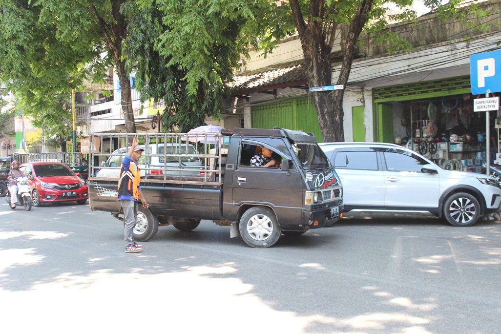 BERJEJER: Petugas jukir mengatur kendaraan yang diparkir di area Jalan Diponegoro, Kelurahan Bangselok, Kecamatan Kota Sumenep, Senin (11/9). (ERWIN MAULYDIN MAASBACH/JPRM)