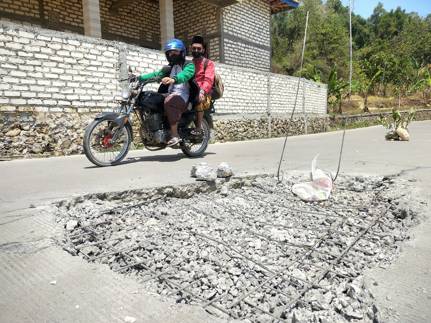 DIBONGKAR: Pengendara melintas di samping jalan rusak akses Jalan Kotah&ndash;Tambelangan yang dibongkar Selasa (12/9). (ANIS BILLAH/JPRM)