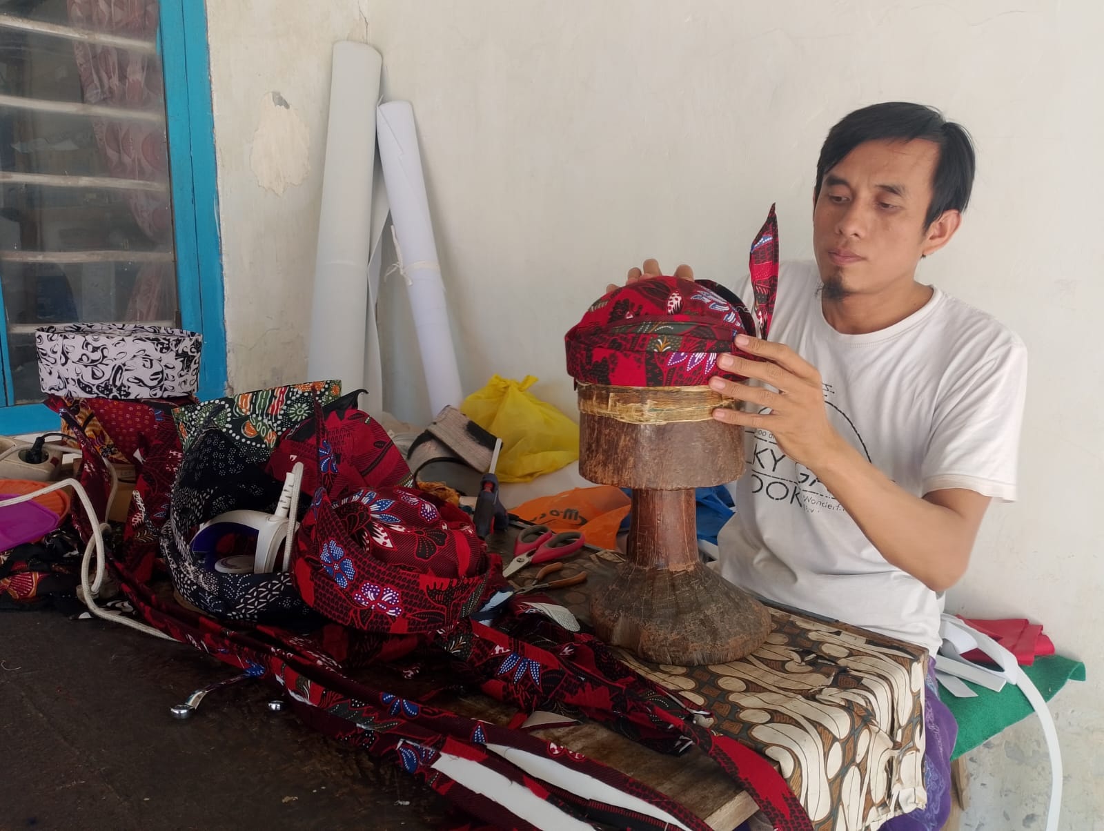 BERBUAH MANIS: Ghafiruddin membuat odheng pesanan pelanggan di rumahnya yang terletak di Desa Pademawu Barat, Kecamatan Pademawu, Pamekasan. (UBAIDILLAHIR RA&rsquo;IE/JPRM)