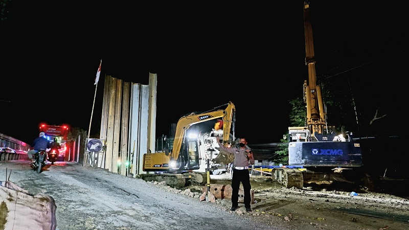 SIAGA: Polisi berjaga dan mengatur kendaraan yang melintasi Jembatan Klampis di Kecamatan Jrengik, Sampang, Sabtu (23/9) malam. (MOH. IQBAL AFGANI/JPRM)