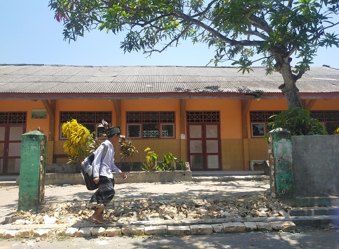 BELUM DIGELAR: Bocah berjalan di depan SDN Pejagan 9 yang mendapat program rehabilitasi dari Dispendik Bangkalan, Selasa (26/9). (VIVIN AGUSTIN HARTONO/JPRM)