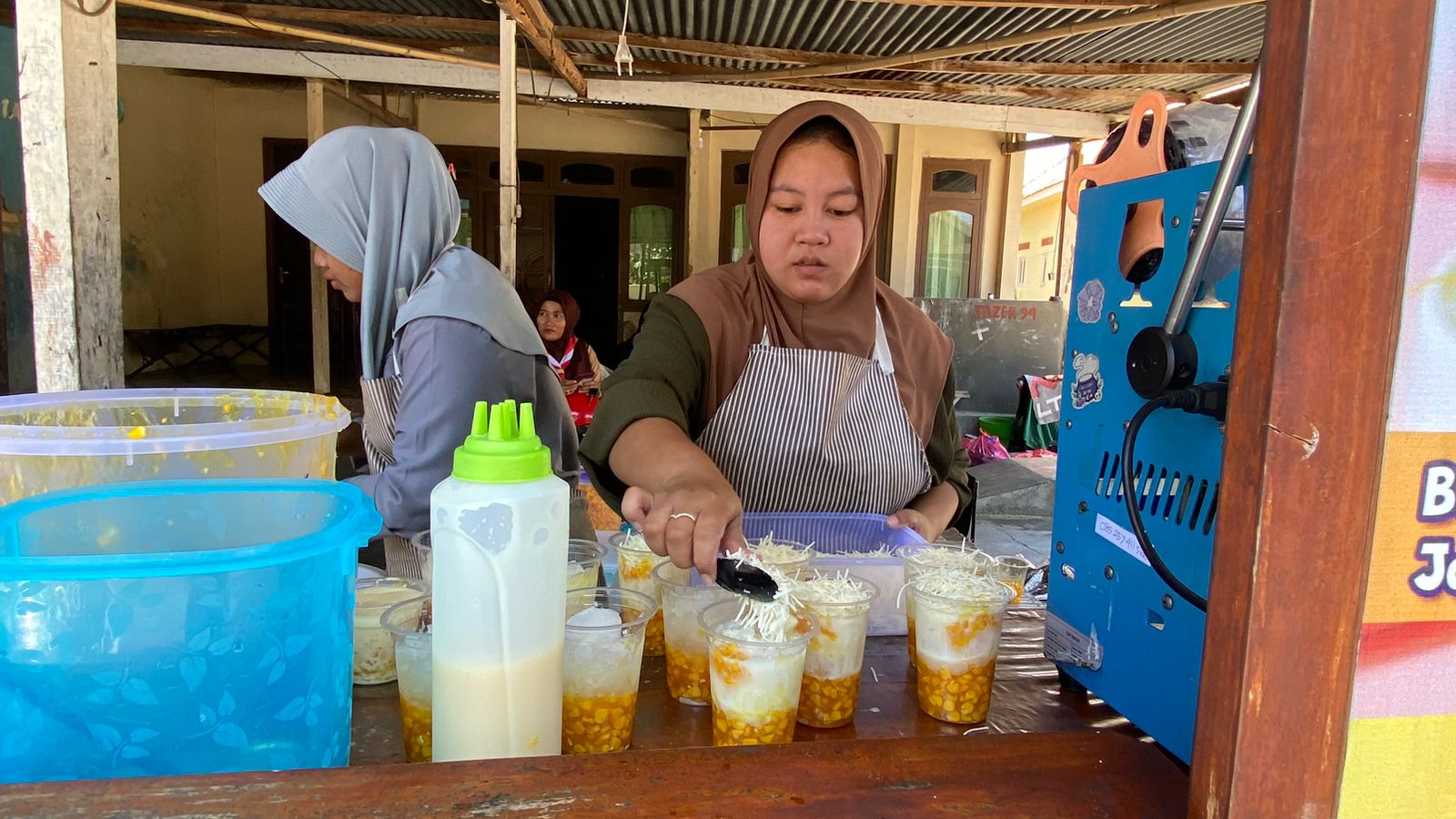 VIRAL: Putri Ayu Wulandari (kerudung cokelat) melayani pelanggan es jagung di Desa Kolpajung, Kecamatan Pamekasan, Sabtu (30/9). (AYU LATIFAH/JPRM)