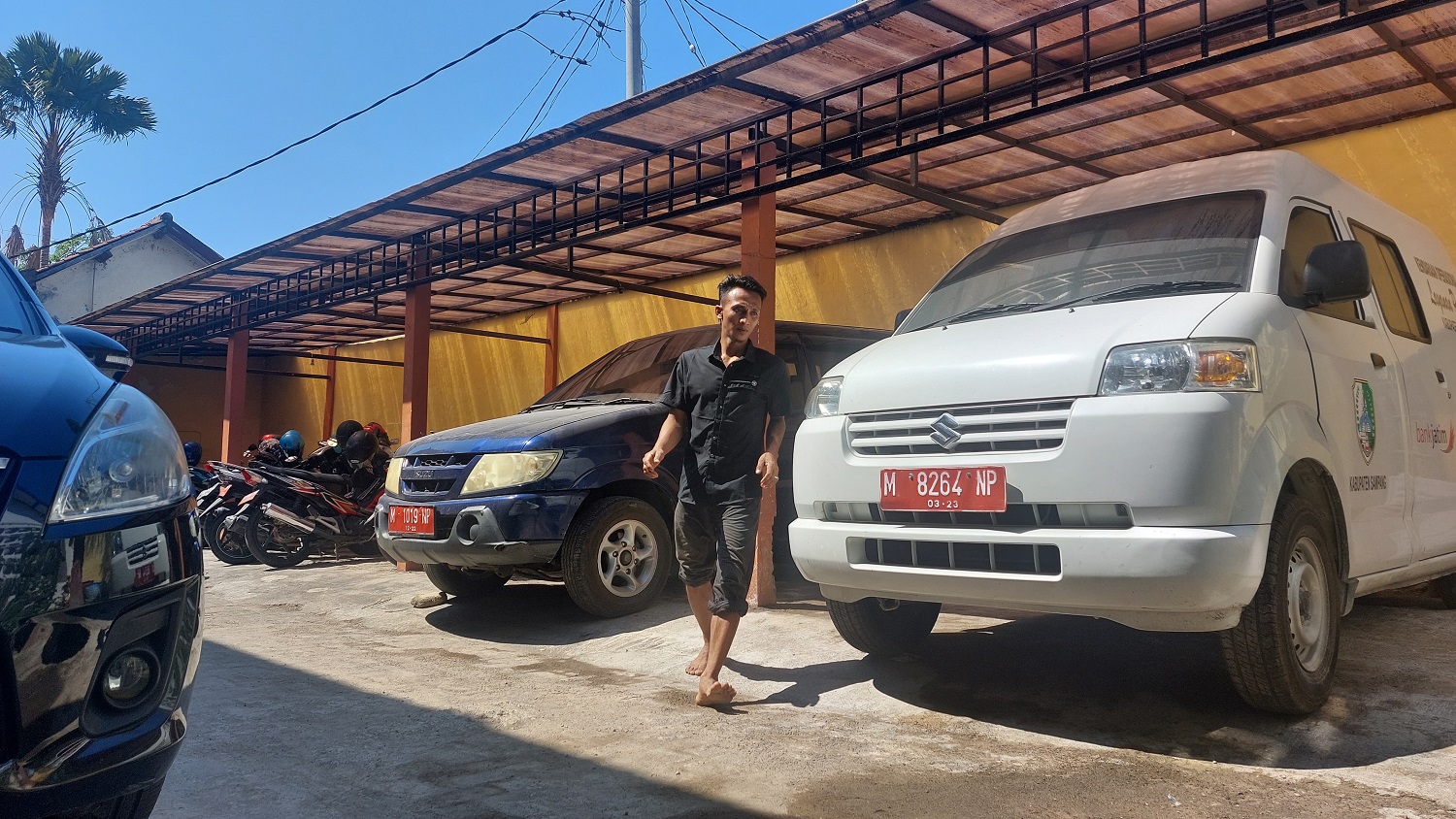 MILIK PEMERINTAH: Warga berada di sekitar mobdin yang terparkir di halaman kantor BPPKAD Sampang Senin (2/10). (JUNAIDI PONDIYANTO/JPRM)