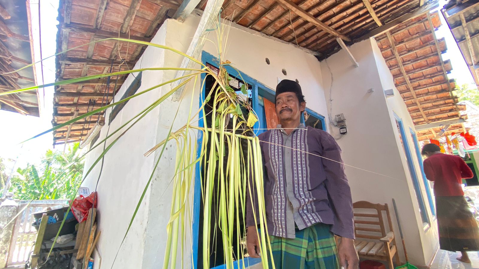 TURUN-TEMURUN: Sahrandi menggantung janur kuning di depan rumahnya, Minggu (24/9). (AYU LATIFAH/JPRM)