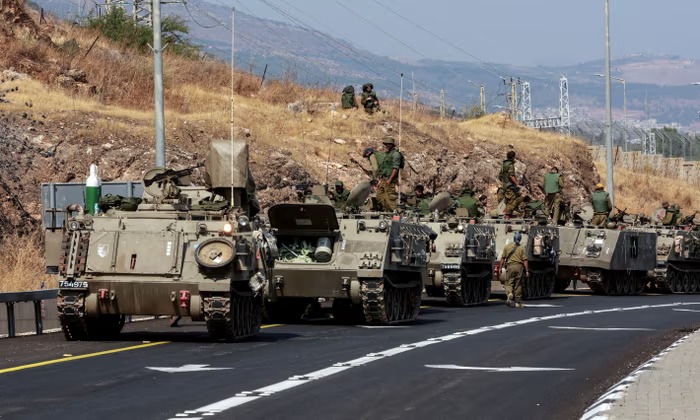 MENYAPA: Konvoi pengangkut personel lapis baja Israel (APC) melaju di jalan dekat perbatasan Israel dengan Lebanon, Israel Utara, Senin (9/10) (Sumber: THE GUARDIAN)