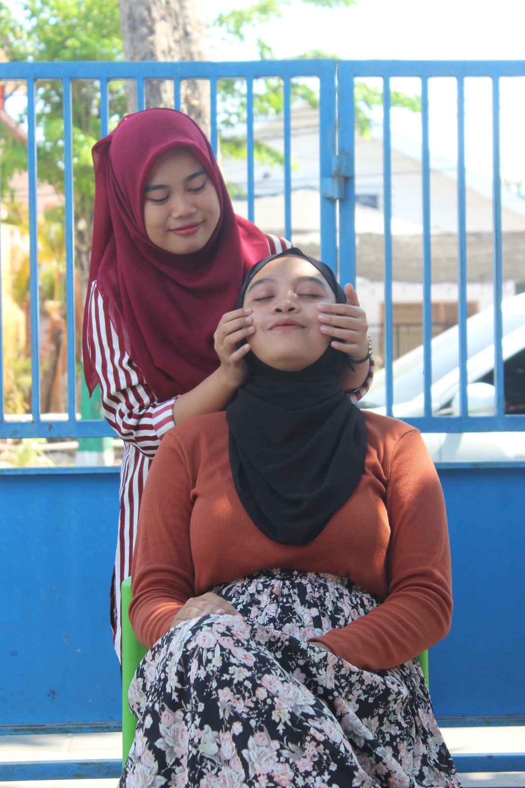 MERAWAT KULIT: Eva Maulidea Rindiany (kerudung merah) memijat wajah Abroriyah di Pamekasan, Jumat (13/10). (FAHMI JALIL JPRM)