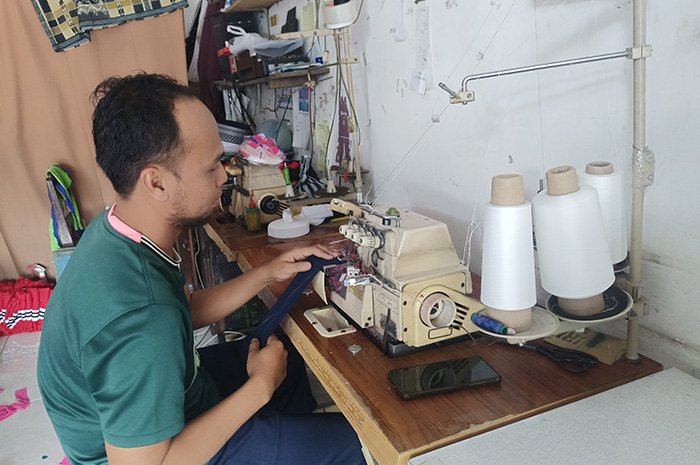 SUKSES: Sudarsono, pengusaha konfeksi sedang membuat baju sekolah di toko miliknya yang berlokasi di Desa Batuan, Kecamatan Batuan, Sabtu (19/8). (MOH IQBAL/JPRM)