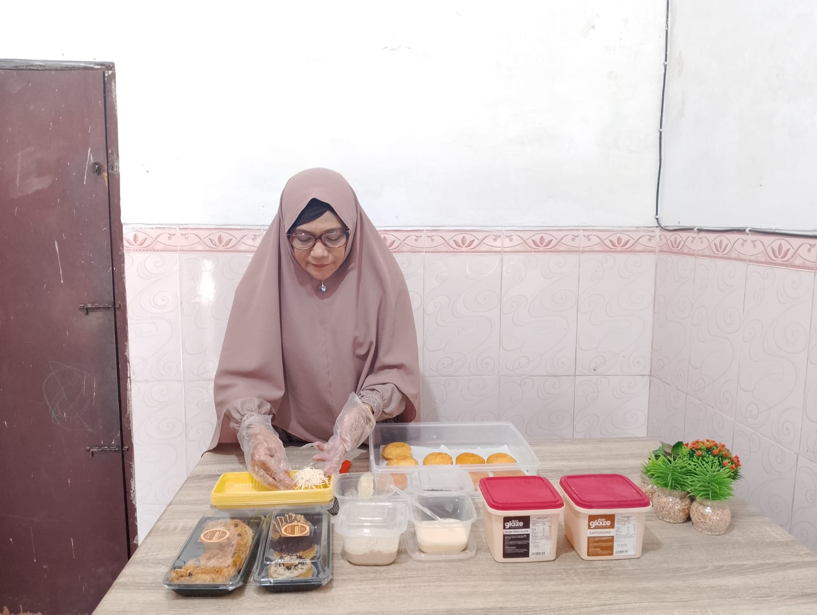 TELATEN: Titing Erlinawati memasang topping donat pesanan pelanggan di rumahnya Desa Murtajih, Kecamatan Pademawu, Pamekasan, Ssabtu (21/10). (UBAIDILLAHIR RA&rsquo;IE/JPRM)