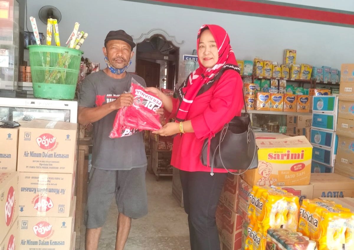 DEKAT DENGAN RAKYAT: Pengurus DPC PDI Perjuangan Bangkalan Farida menyerahkan kaus bergambar Ganjar Pranowo ke warga di Kelurahan Kraton, Minggu (29/10). (DPC PDI BANGKALAN UNTUK JPRM)