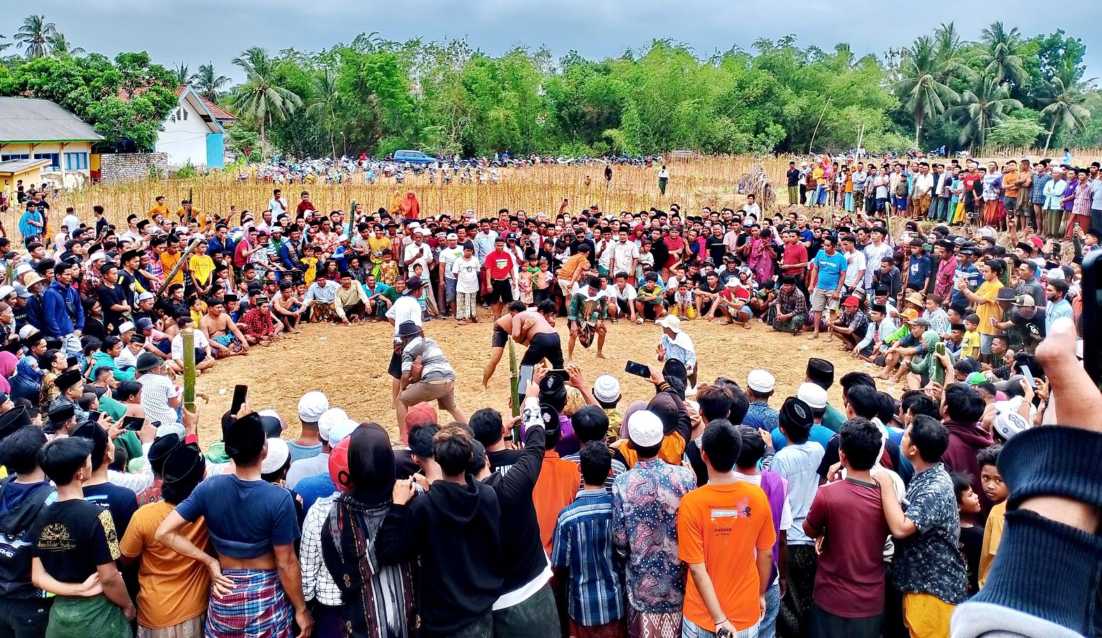 MEMUKAU: Warga menyaksikan peserta okol yang bertanding di arena, Dusun Bunut, Desa Plakpak, Kecamatan Pegantenan, Pamekasan, Jumat (3/11). (UBAIDILLAHIR RA&rsquo;IE/JPRM)