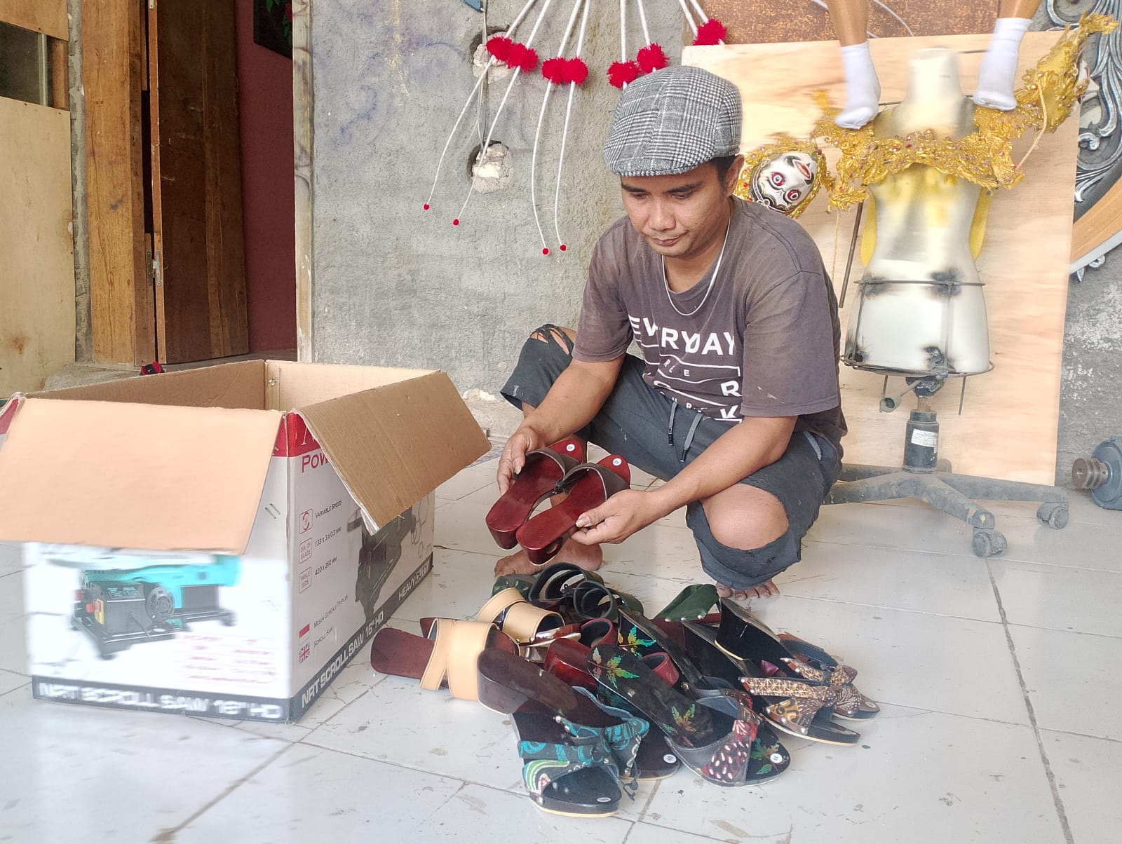 PRODUKTIF: Kandarusman mengemas bakiak siap kirim ke pelanggan di rumahnya Desa Tanjung, Kecamatan Pademawu, Pamekasan, Sabtu (4/11). (UBAIDILLAHIR RA&rsquo;IE/JPRM)