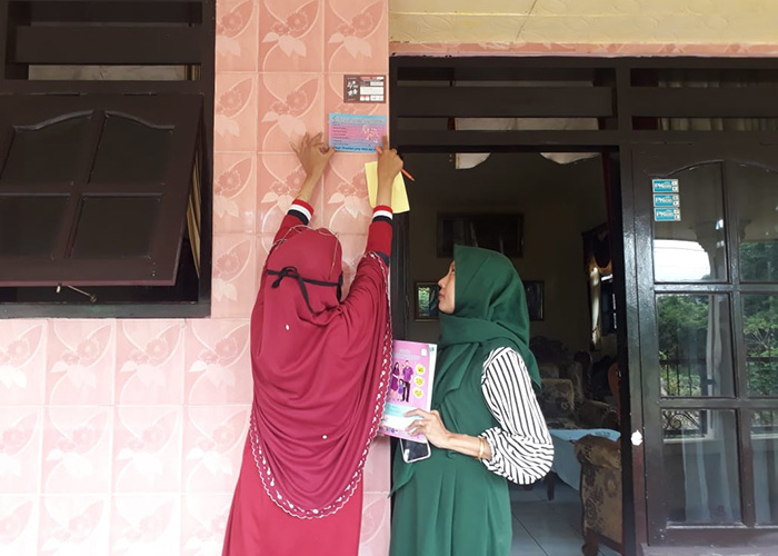DOOR-TO-DOOR: Kader kesehatan Puskesmas Talango memasang stiker Gardu Turis ke rumah ibu hamil dan menyusui wilayah kerja. (PUSKESMAS TALANGO UNTUK JPRM)