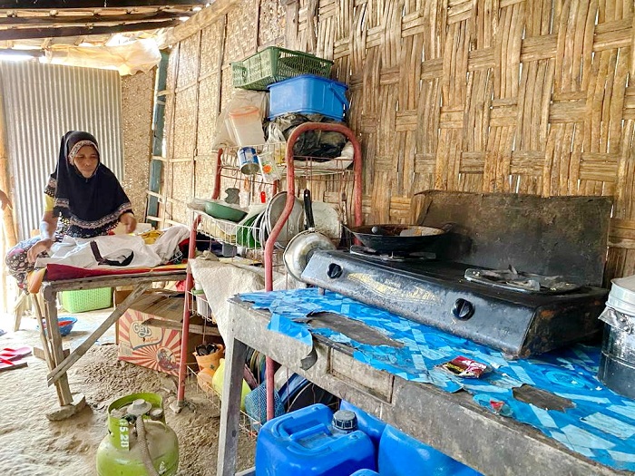 HIDUP SEADANYA: Soibah melipat baju di tempat tidur sekaligus dapurnya di Dusun Bulungan, Desa Plakaran, Kecamatan Jrengik, Sampang. (ANIS BILLAH/JPRM)