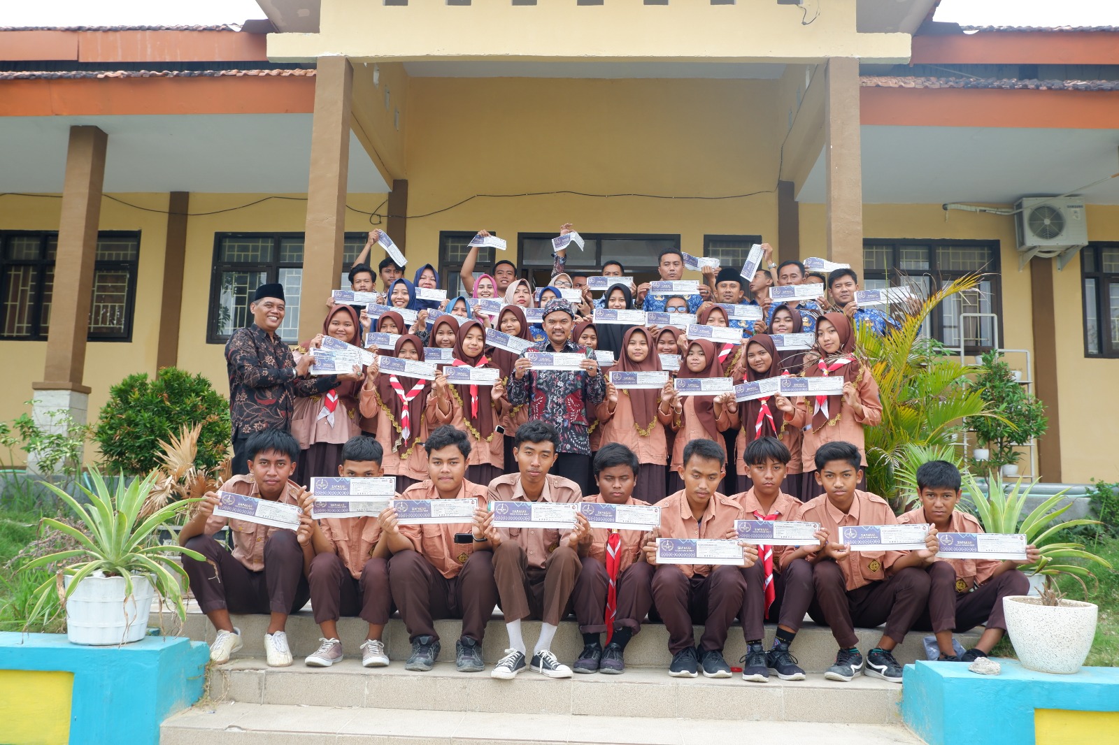 SATU SUARA: Kepala SMKN 1 Blega Suieb (tengah, baris kedua) berfoto dengan siswa menunjukkan balot dukungan untuk Pinky Hidayati, Jumat (10/11). (SMKN 1 BLEGA UNTUK JPRM)