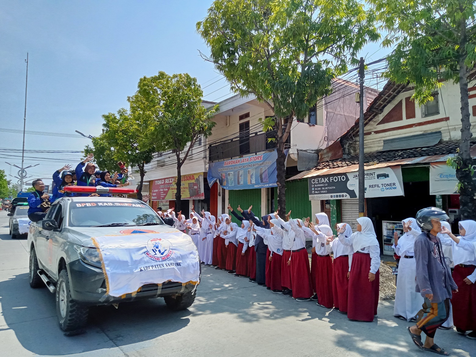 BERPRESTASI: Atlet disambut oleh siswa di sepanjang jalan perkotaan Sampang, Senin (18/9). (MOH. IQBAL AFGANI/JPRM)