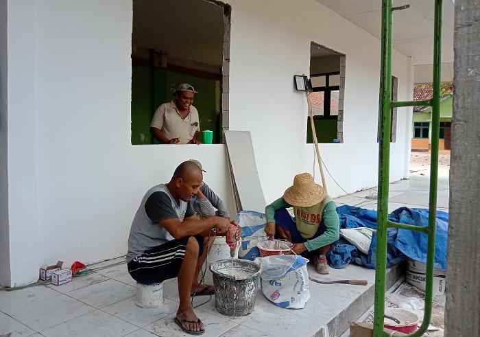 BARU PENGECATAN TEMBOK: Pekerja bersiap mengecat tembok proyek SDN Talang 2, Kecamatan Saronggi, Sumenep, Minggu (19/11). (M. ERWIN/JPRM)