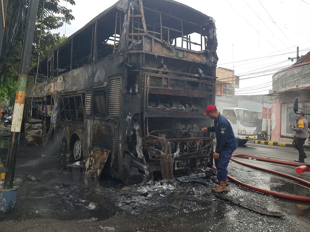 KOBONG: Petugas pemadam kebakaran berada di dekat bus Karina double decker B 7036 PRN Jakarta&ndash;Madura yang terbakar di Jalan Jokotole, Kelurahan Barurambat Kota, Pamekasan, Selasa (28/11). (LAILIYATUN