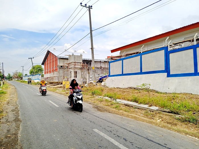 BELUM TUNTAS: Warga melintas di depan proyek SIHT di Desa Gugul, Kecamatan Tlanakan, Pamekasan, Sabtu (2/12). (FAHMI JALIL/JPRM)