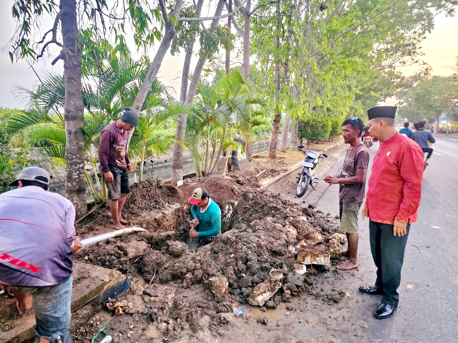 TINGKATKAN LAYANAN: Direktur PDAM Sumber Sejahtera Bangkalan Sjobirin Hasan (baju merah) memantau perbaikan saluran air di Jalan Halim Perdanakusuma, Sabtu (16/10). (PDAM SUMBER SEJAHTERA BANGKALAN)