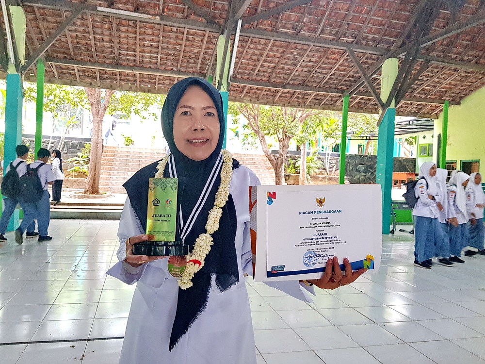 TELADAN: Chandra Kirana menunjukkan trofi dan piagam penghargaan juara tiga GTK Berprestasi dari Kementerian Agama, Senin (27/11). (LAILIYATUN NURIYAH/JPRM)