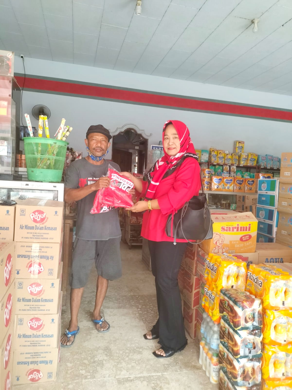 DOOR-TO-DOOR: Bendahara DPC PDI Perjuangan Bangkalan Farida menyerahkan kaus kepada warga di Kelurahan Kraton.&nbsp;(PDI PERJUANGAN UNTUK JPRM)